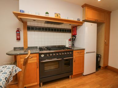 A kitchen with a stove oven refrigerator wooden cabinets and a fire extinguisher at Blue Hill House in Ambleside
