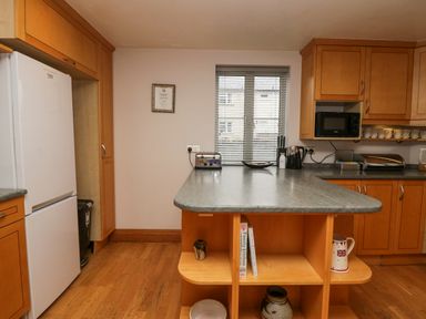 A kitchen with wooden cabinets a refrigerator a countertop island and appliances at Blue Hill House in Ambleside