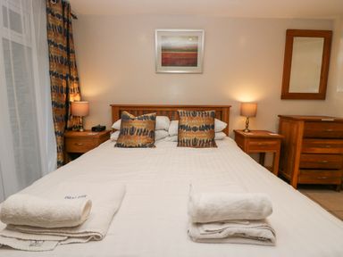 A bedroom with a double bed with patterned pillows two bedside tables with lamps a chest of drawers and a mirror at Blue Hill House Ambleside