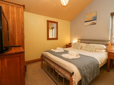A bedroom with a bed a wooden wardrobe a mirror and two bedside tables at Blue Hill House Ambleside