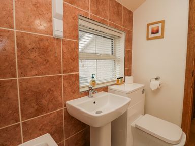 A bathroom with a sink toilet window and toiletries at Blue Hill House in Ambleside
