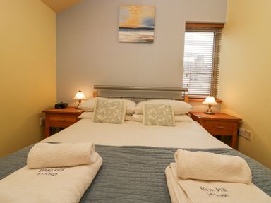 A bedroom with a double bed with folded towels on it two bedside tables with lamps and a window with blinds at Blue Hill House Ambleside