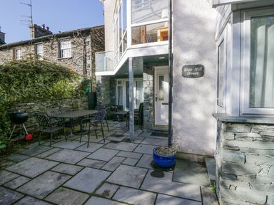 A patio area with outdoor table and chairs and a blue plant pot near a door at Blue Hill House in Ambleside