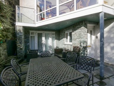 An outdoor patio area with a metal table and chairs and a stone wall at Blue Hill House in Ambleside