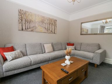 A living room with a gray corner sofa wooden coffee table and a triptych tree painting at Park Beck 3 in Windermere