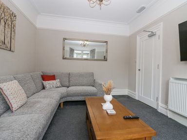 A living room with a gray corner sofa a wooden coffee table a wall mirror and a wall-mounted television at Park Beck 3 in Windermere