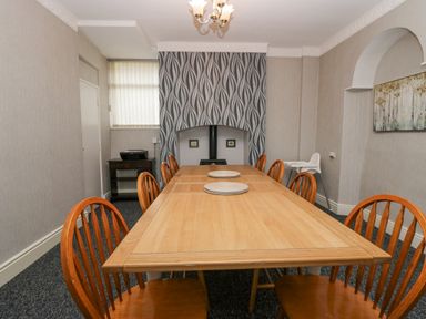 A dining room with a wooden table surrounded by wooden chairs and a high chair at Park Beck 3 in Windermere