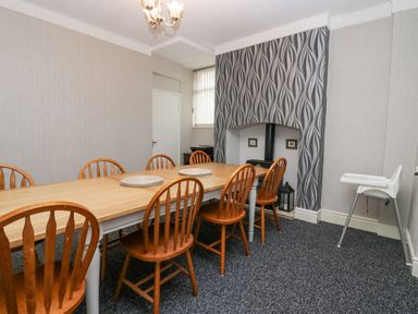A dining room with a wooden table and chairs a high chair and patterned wallpaper at Park Beck 3 in Windermere