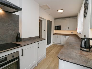 A kitchen with white cabinets a stove a knife holder a kettle and a window at Park Beck 3 in Windermere