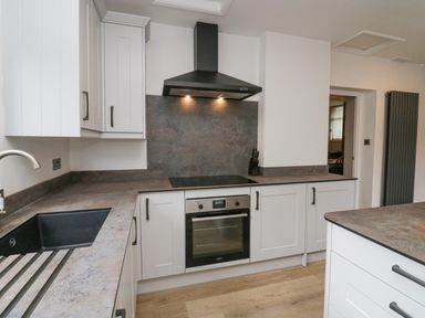 A kitchen with white cabinets black sink stove with oven and a black extractor hood at Park Beck 3 in Windermere