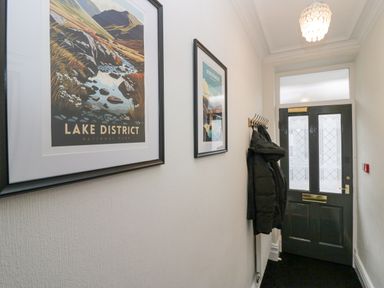 A hallway with framed pictures on the wall coat hooks with jackets and a front door at Park Beck 3 in Windermere