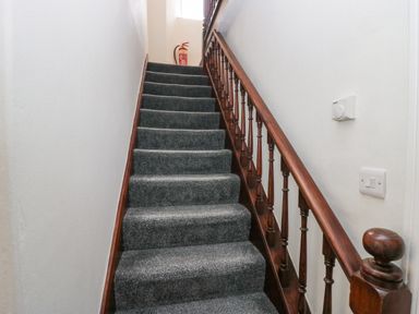 A carpeted staircase with wooden handrail and spindles and a fire extinguisher at the top at Park Beck 3 in Windermere