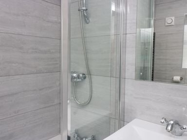 A bathroom with a glass shower enclosure a showerhead a sink with a faucet and a wall mirror at Park Beck 3 in Windermere