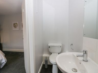 A small bathroom with a toilet and sink next to a bedroom at Park Beck 3 in Windermere