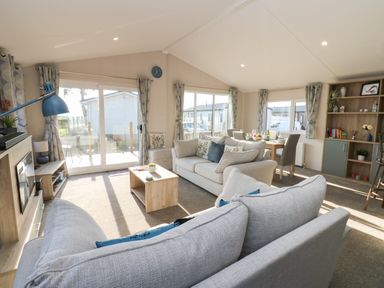 A living room with two sofas a coffee table a dining table and shelves at Brocklebank Lodge 35 High Hesket near Armathwaite