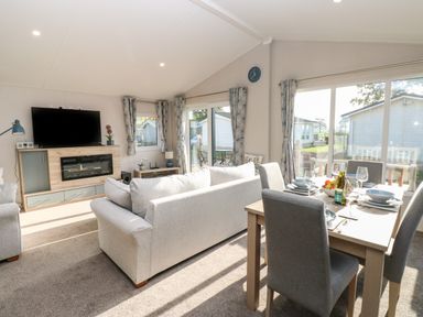 An open living and dining area with sofas a television fireplace and a dining table set at Brocklebank Lodge 35 High Hesket near Armathwaite