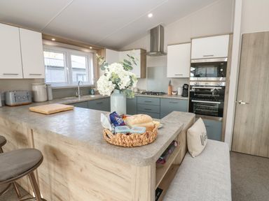 A kitchen with a countertop vase of flowers bread and snacks at Brocklebank Lodge 35 in High Hesket near Armathwaite