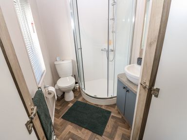A bathroom with a shower enclosure toilet sink and towel at Brocklebank Lodge 35 High Hesket near Armathwaite