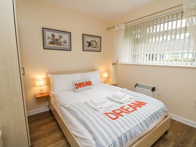 A bedroom with a double bed two bedside lamps and framed pictures of dogs on the wall at Trem-Yr-Afon in Aberaeron