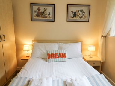A bedroom with a bed two lamps a wardrobe and dog paintings at Trem-Yr-Afon in Aberaeron