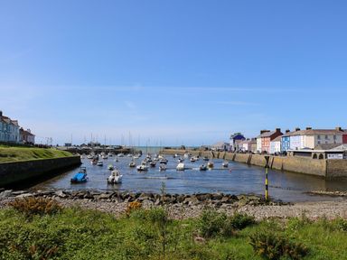 A small harbor with boats anchored on the water and buildings along the waterfront at Trem-Yr-Afon in Aberaeron