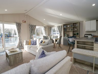 A living room with sofas dining table chairs and shelving unit at The Three Bears Lodge Coniston Drive 11 South Lakeland Leisure Village near Warton