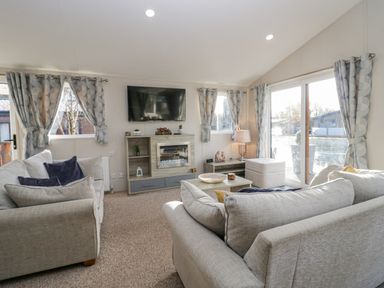 A living room with two sofas a coffee table a television and a fireplace at The Three Bears Lodge Coniston Drive 11 South Lakeland Leisure Village near Warton