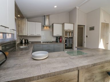 A kitchen with countertop sink stove oven and microwave at The Three Bears Lodge Coniston Drive 11 South Lakeland Leisure Village near Warton