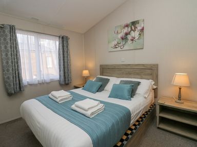A bedroom with a double bed two bedside tables with lamps and a window with curtains at The Three Bears Lodge Coniston Drive 11 South Lakeland Leisure Village near Warton