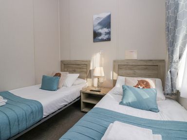 A bedroom with two single beds a side table with lamp and a mountain picture on the wall at The Three Bears Lodge Coniston Drive 11 South Lakeland Leisure Village near Warton