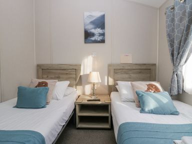 A bedroom with two single beds a bedside table and a lamp at The Three Bears Lodge Coniston Drive 11 South Lakeland Leisure Village near Warton