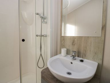 A bathroom with a shower enclosure a sink with a faucet a mirror and a cup on the counter at The Three Bears Lodge Coniston Drive 11 South Lakeland Leisure Village near Warton