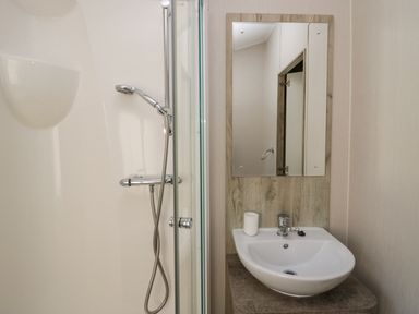 A bathroom with a shower and a sink with a mirror above at The Three Bears Lodge Coniston Drive 11 South Lakeland Leisure Village near Warton
