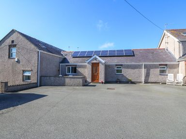 A single story house with solar panels on the roof and a paved driveway at Gwynlys in Cemaes Bay
