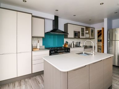 A kitchen with an island countertop sink stove and refrigerator at Carousel in Broad Haven