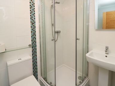 A bathroom with a shower enclosure a toilet and a sink at Carousel in Broad Haven