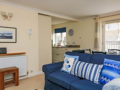 A living room with a blue sofa and pillows next to a dining table and an open kitchen at 8 Dartmouth House in Dartmouth