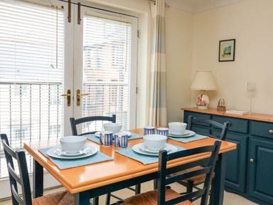 A dining room with a wooden table set for four and dark blue chairs at 8 Dartmouth House in Dartmouth