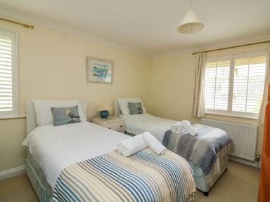 A bedroom with two single beds with blankets and rolled towels on them a bedside table with a lamp and framed artwork on the wall at 8 Dartmouth House in Dartmouth