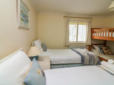 A bedroom with two single beds a wooden bunk bed a window with curtains and a bedside table with a lamp at 8 Dartmouth House in Dartmouth