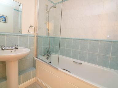 A bathroom with a bathtub shower combination and a pedestal sink at 8 Dartmouth House in Dartmouth