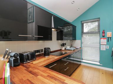A kitchen with black cabinets wooden countertops toaster kettle and window with blinds at 12 Blue Hill Park in Ambleside