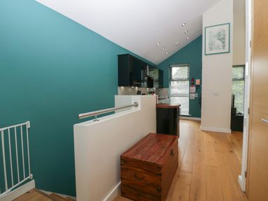 A hallway with wooden floor a chest and teal walls at 12 Blue Hill Park in Ambleside