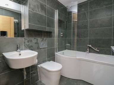 A bathroom with a wall-mounted sink toilet and bathtub with shower at 12 Blue Hill Park Ambleside