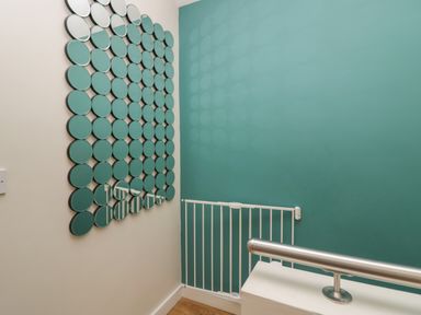 A wall with circular mirrors near a white baby gate and a metal handrail at 12 Blue Hill Park in Ambleside