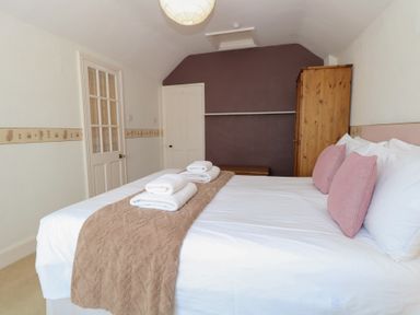 A bedroom with a bed and towels at Iona Cottage Southwold