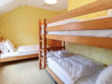 A bedroom with a bunk bed and a single bed at Iona Cottage Southwold