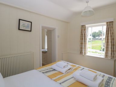 A bedroom with a bed and towels at Iona Cottage Southwold