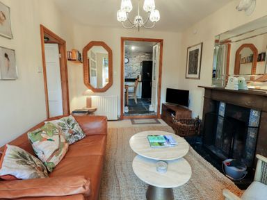 A living room with a brown leather sofa and coffee tables near a fireplace and a television at Riverbank At Stepping Stones in Rydal