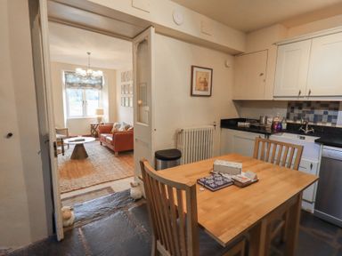 A kitchen with a wooden dining table and chairs next to a living room with a sofa and coffee table at Riverbank At Stepping Stones in Rydal